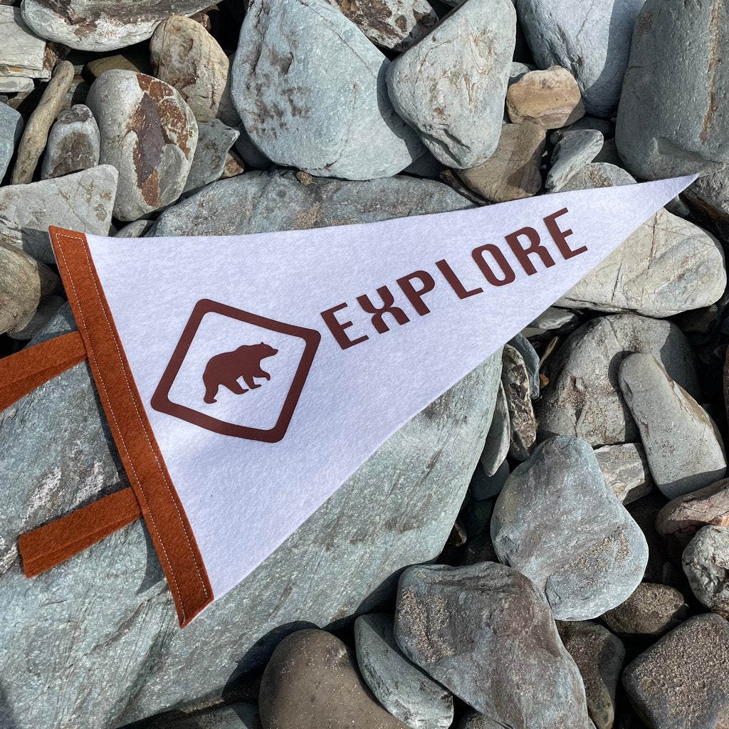Explore pennant flag in white and bown with a bear design on a pebble beach