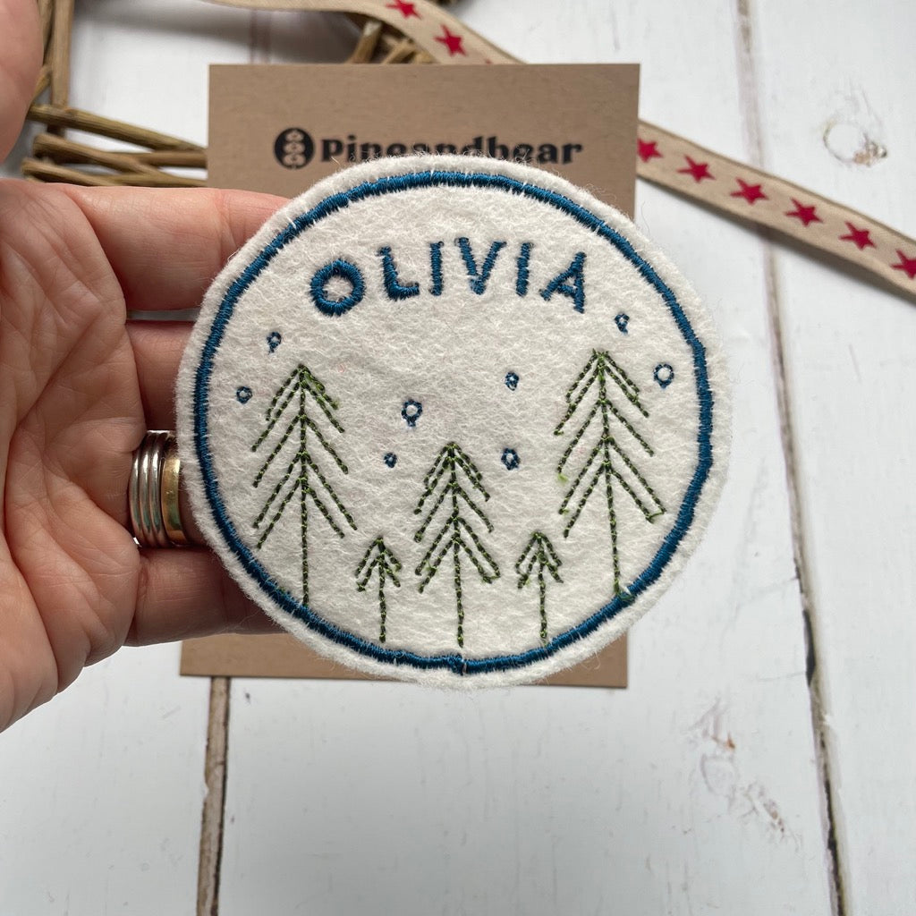 Personalised Christmas name patch for children featuring a festive fir trees design.