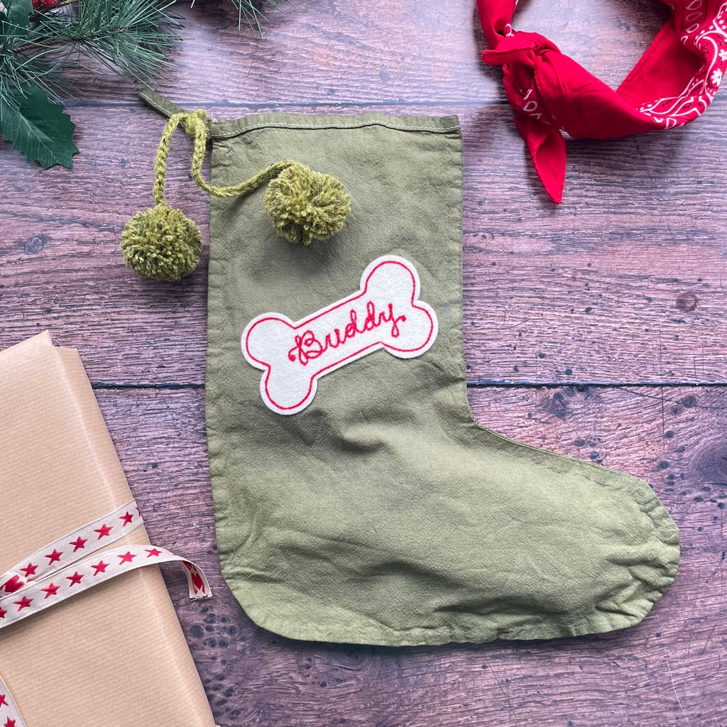 Green Christmas stocking with a custom dog patch shaped like a bone on the front.