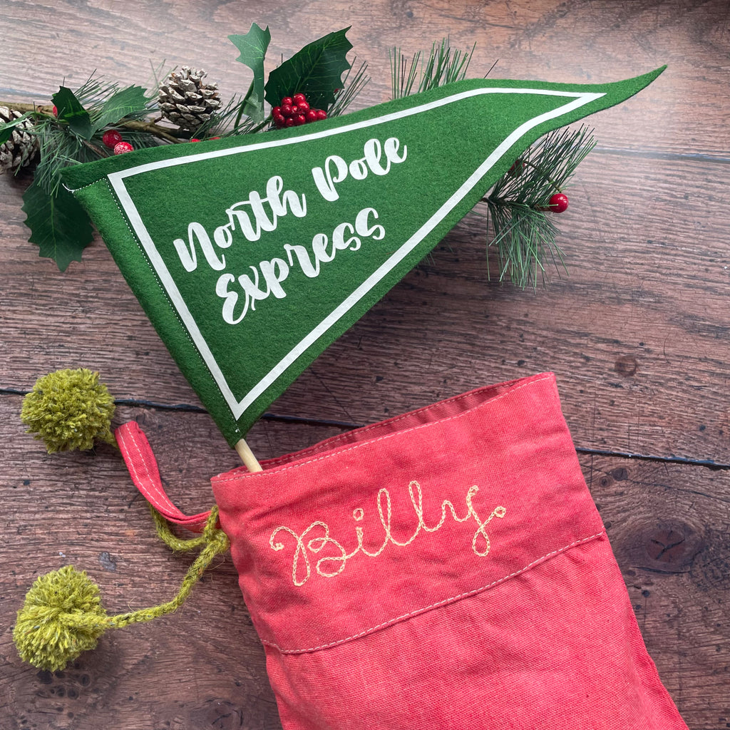 North Pole Express Pennant Flag in green and white poking out the end of a Christmas stocking.