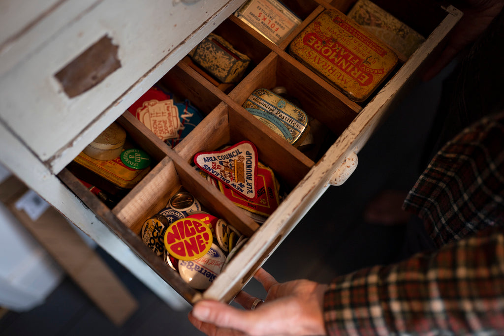 A drawer being opened with lots of vintage tins and patches in.