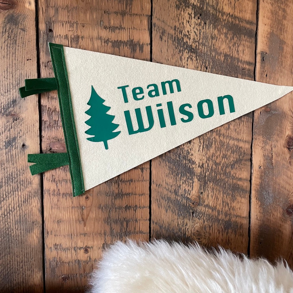 Team pennant flag in cream and green with a tree design on a wooden wall