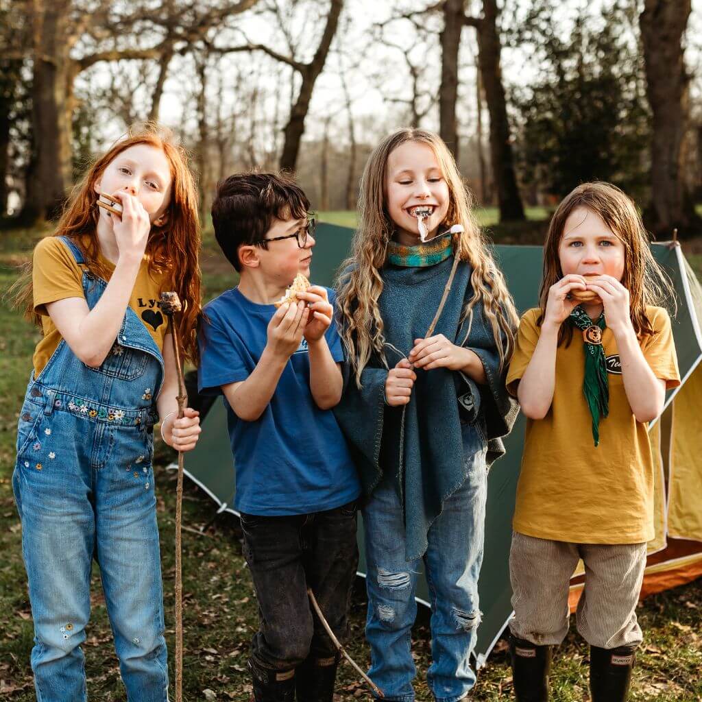 Four children eating marshmallows in a field