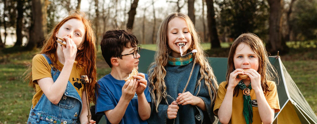 Four children eating marshmallows in a field 