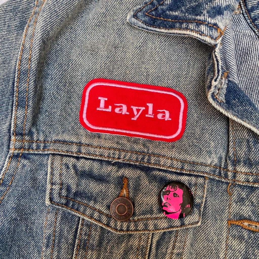 Custom embroidered name patch in yred and pink on a denim jacket.