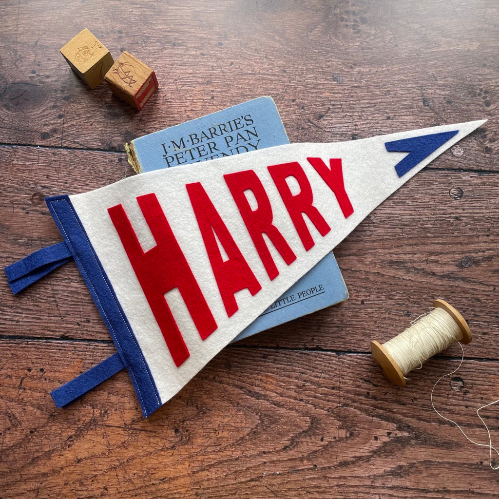 Personalised pennant flag in white, blue and red on a wooden table and peter pan book