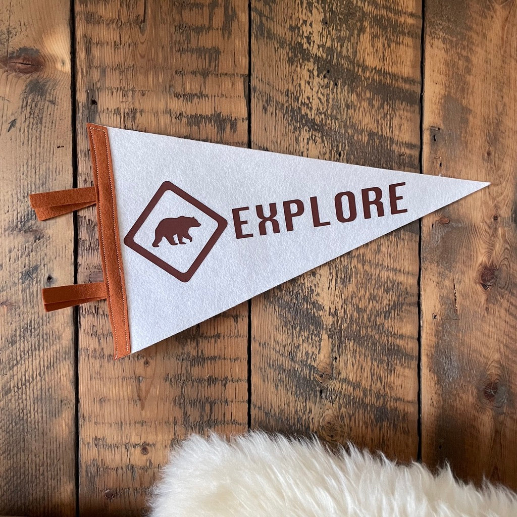 Explore pennant flag in white and bown with a bear design on a wooden wall