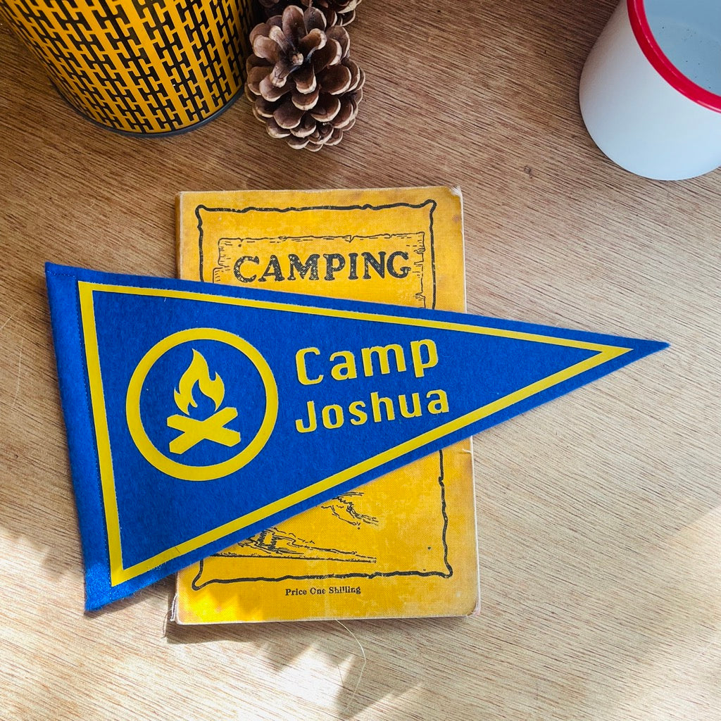A custom camp mini pennant flag with a campfire design in blue and mustard
