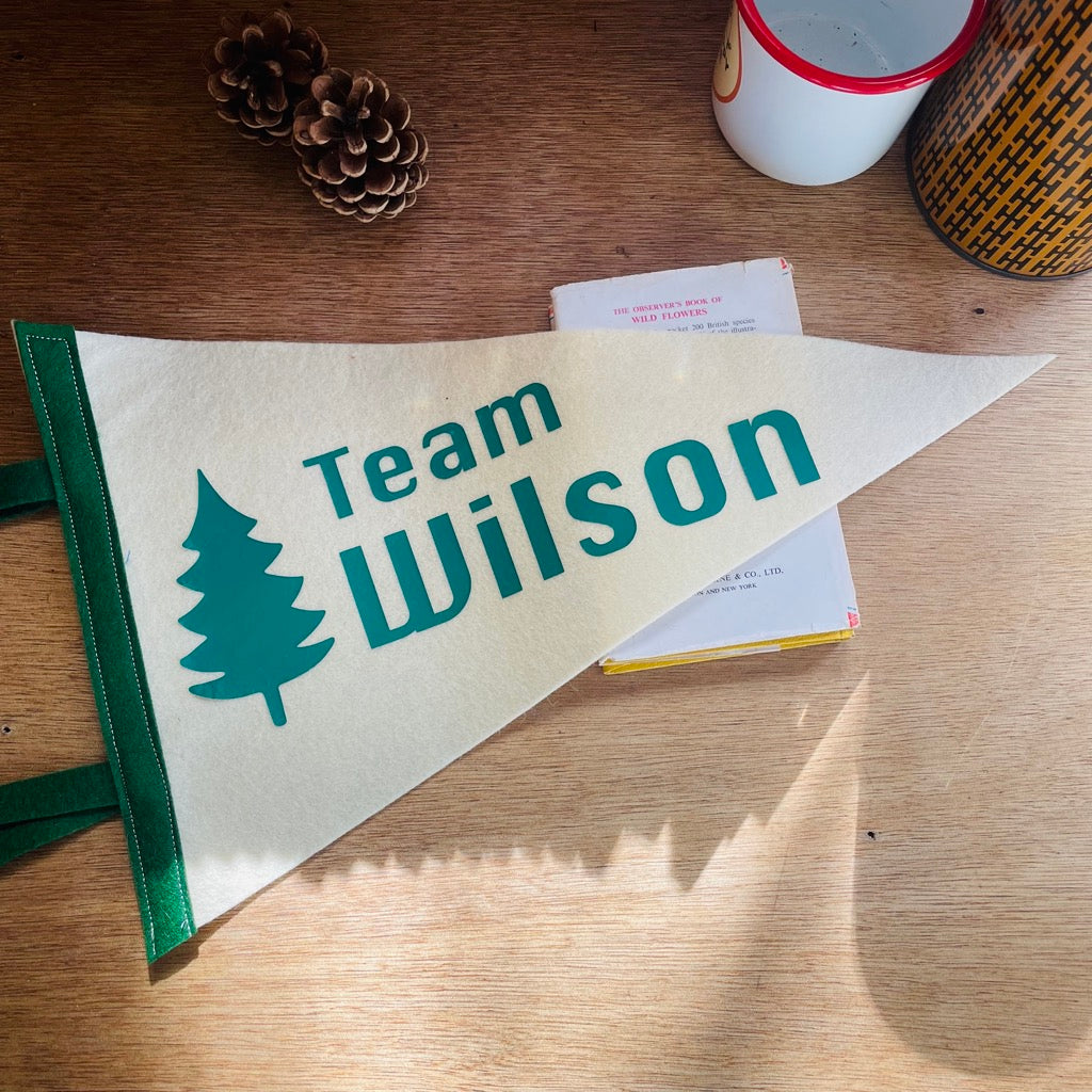 Team pennant flag in cream and green with a tree design on a wooden desk