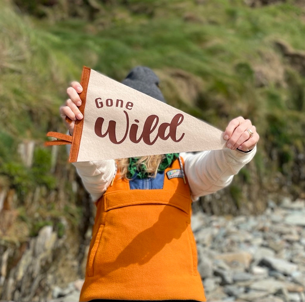 Gone Wild pennant flag in browns  being held by a girl in an orange top