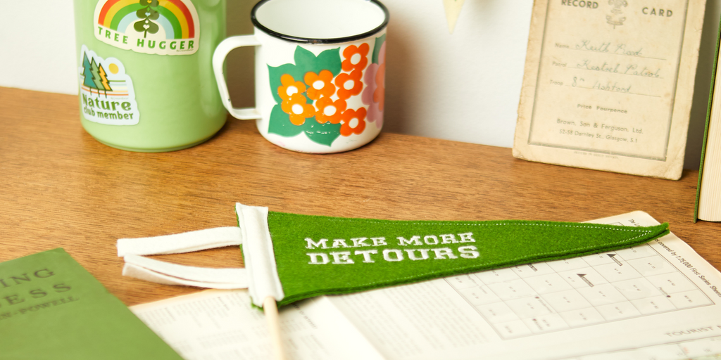 A desk with a vintage mug and flask and 2 mini pennant flags