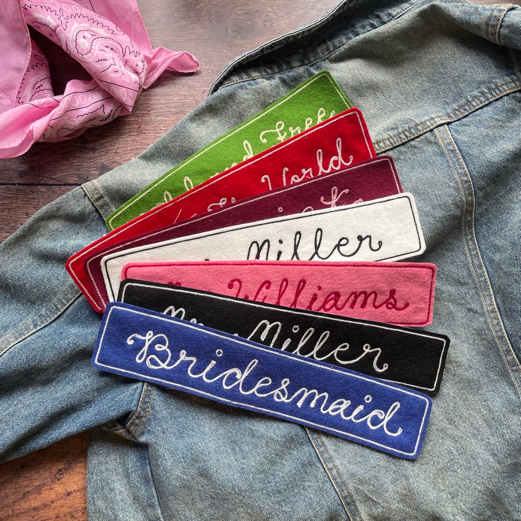 A selction of large vintage chain stitch jacket patches i bright colours lying on a denim jacket
