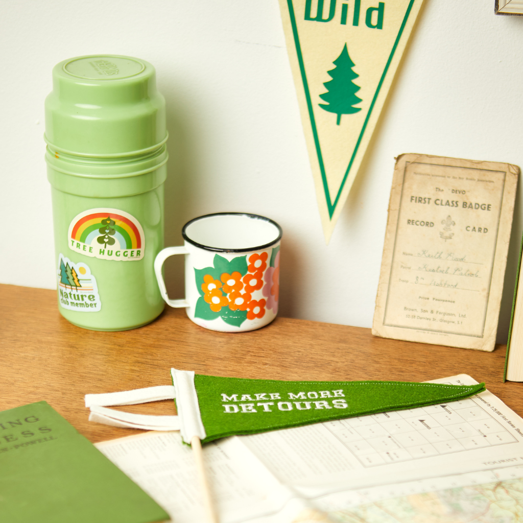 A desk with a vintage mug and flask and 2 mini pennant flags