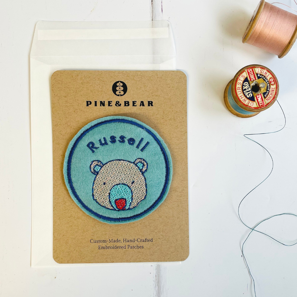 A personalised embroidered name patch with a bear design.