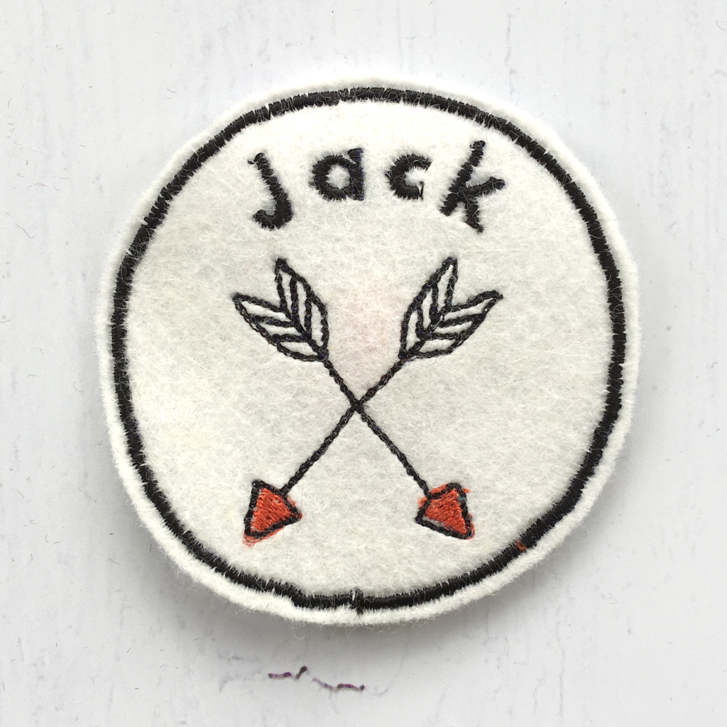 An embroidered name patch with an arrow design.